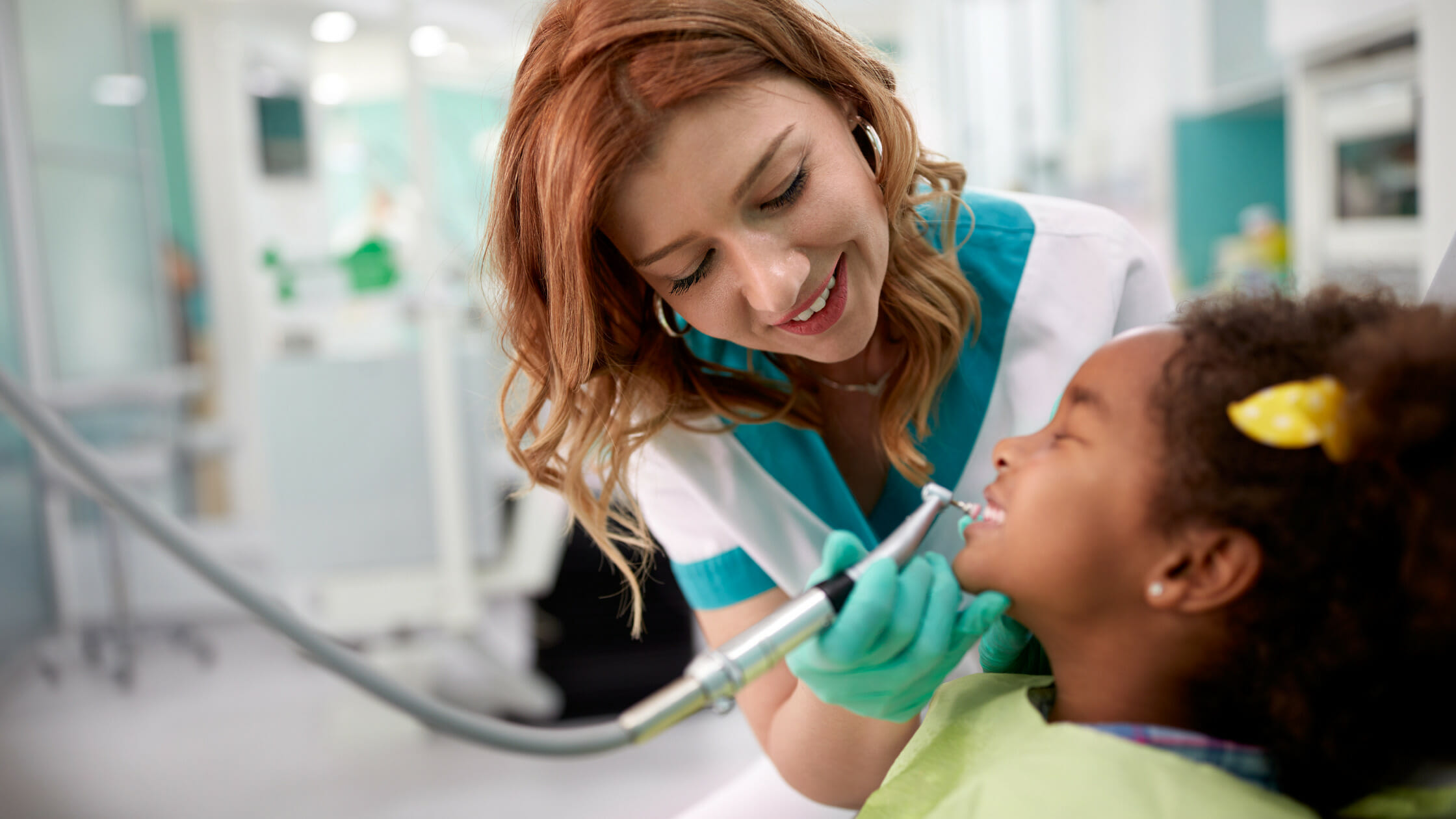 Dental assistant cleaning a child's teeth